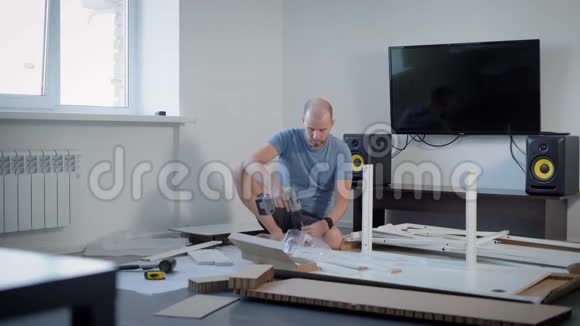 一个成年人用螺丝刀把螺丝或螺栓固定在桌子的底部这个人把家具收集在桌子上视频的预览图