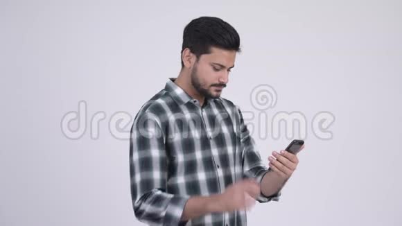 年轻的留着胡子的印度男人用电话得到好消息视频的预览图