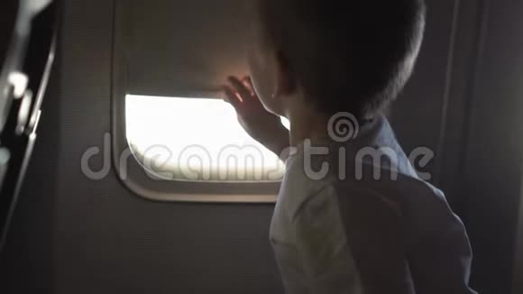 小男孩坐在座位上打开飞机窗视频的预览图
