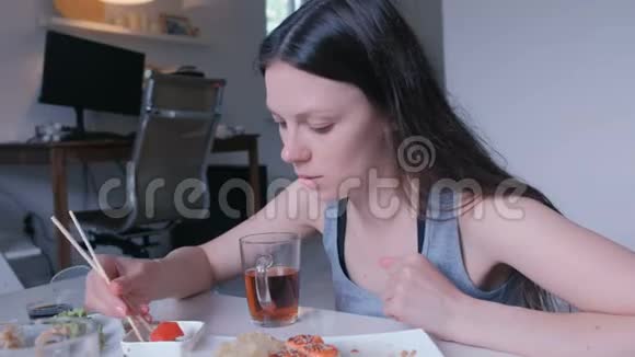 年轻的黑发女人在家里用木棍吃面包视频的预览图