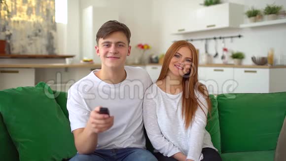 幸福的一对夫妇坐在沙发上在客厅里一起看电视慢动作视频的预览图