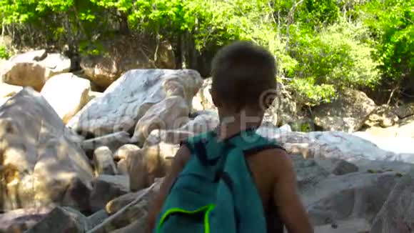 旅游男孩在石河上的木桥上行走在山上爬山在吊桥上散步的男孩游客视频的预览图