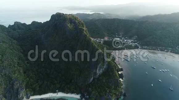 空中无人机拍摄的高山覆盖热带森林和船只锚定在海湾热带景观视频的预览图