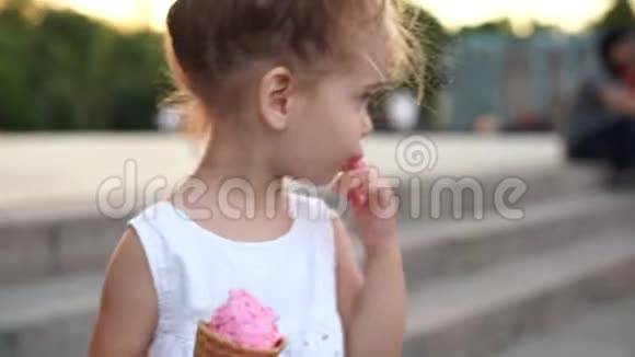 可爱的白种人小女孩喜欢在公园散步的华夫饼锥冰淇淋孩子吃明亮的冰淇淋视频的预览图