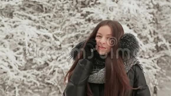 美丽的少女在雪地里杉树的背景上打电话下雪了冬天室外冬季视频的预览图