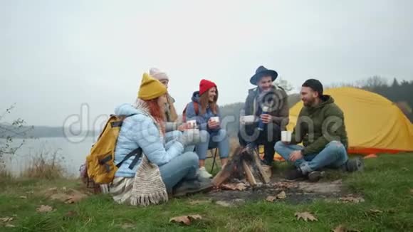 一群微笑的朋友围着篝火露营视频的预览图
