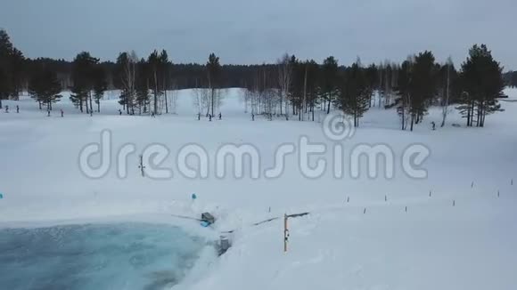 冬季参加滑雪比赛和在靠近森林的滑雪道上跑步的运动员的空中视野录像视频的预览图