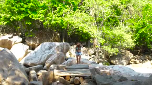 夏季徒步旅行时游客妇女在山河上的桥上散步在热带河桥上散步的年轻女子视频的预览图