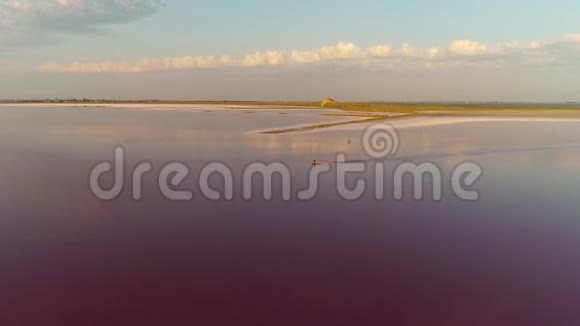 从高处到一个人从事风筝冲浪的粉红色大湖的景色蓝天白云视频的预览图