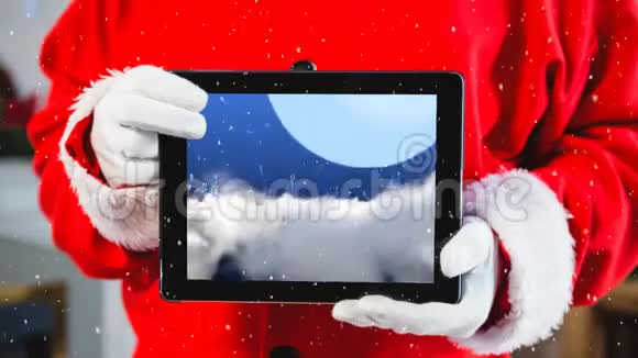 圣诞老人托着平板电脑的躯干上积雪的视频构图视频的预览图