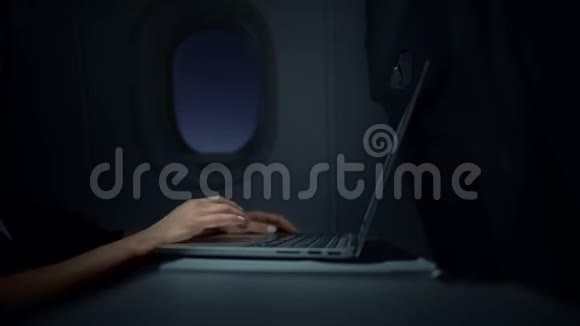 在夜间飞机上拿着笔记本电脑工作的面目全非的女商人视频的预览图