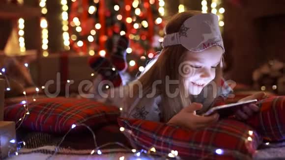 在圣诞树附近玩平板电脑智能手机的女孩视频的预览图