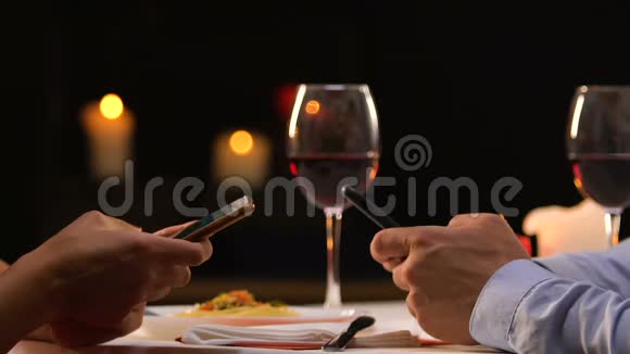 一对夫妇坐在餐厅里滚动着智能手机忽视了真正的交流视频的预览图