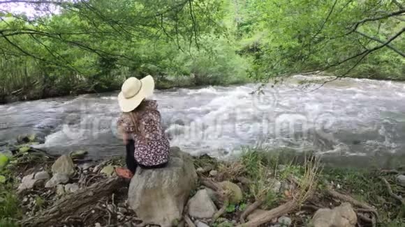 坐在河边戴帽子的年轻女人法国视频的预览图