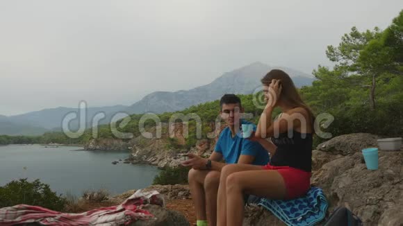 年轻夫妇坐在森林里的岩石上野餐视频的预览图