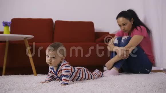悲伤的母亲抱着膝盖看着婴儿视频的预览图