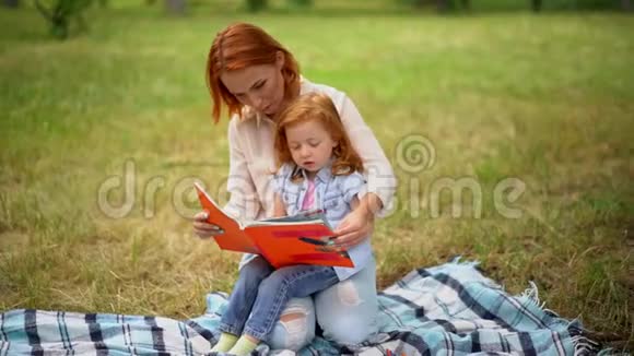 妈妈和女儿在公园里读一本书视频的预览图