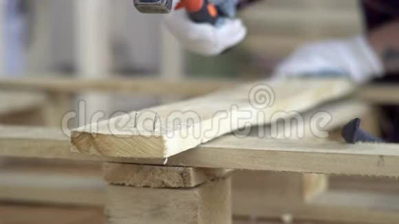 用木质材料作业主人把钉子钉进木板然后转动把钉子从木条上移开视频的预览图