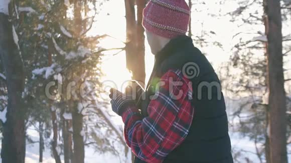 冬天穿着冬衣的人在冬天的森林里在日落时喝着热覆盖的葡萄酒冬天的乐趣慢悠悠的视频的预览图