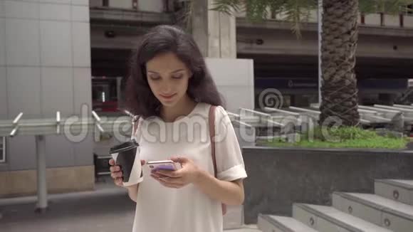 超级慢动作年轻的女士带着电话在城市里散步稳定射击视频的预览图