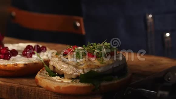 一位身穿蓝色围裙的男厨师在一个炸汉堡包上的美味多汁的鸡肉中加入樱桃股票视频的预览图