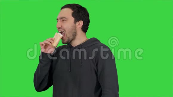 英俊的年轻人在绿色屏幕上吃冰淇淋色度键视频的预览图