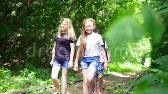 女孩和男孩走在森林里废弃的铁路上视频的预览图