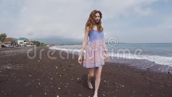 美丽的女孩在黑色的火山沙滩上四处张望视频的预览图