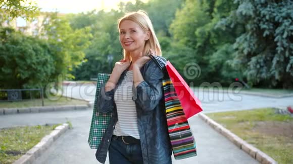 幸福的女人购物狂在户外用购物袋微笑的画像视频的预览图
