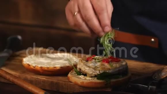男厨师穿蓝色围裙在油炸汉堡包上加入绿色库存录像准备美味的食物视频的预览图