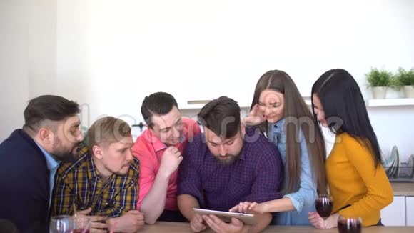 有技术的年轻人朋友们在室内使用数字平板电脑他们正在观看Foto朋友挂了视频的预览图