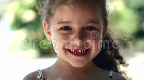 快乐的小女孩卷发带着美丽的微笑和绿色的眼睛看着相机快乐的微笑视频的预览图