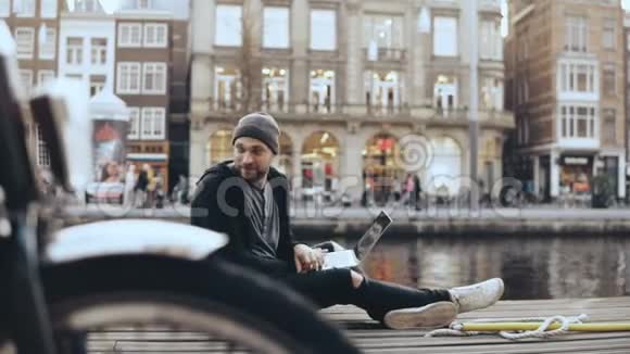 4K欧洲男人坐在街上拿着笔记本电脑摄像机前的自行车轮创意美工移动办公视频的预览图