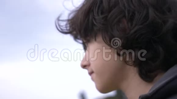可爱的少年卷发对着蓝天4k慢镜头拍摄视频的预览图