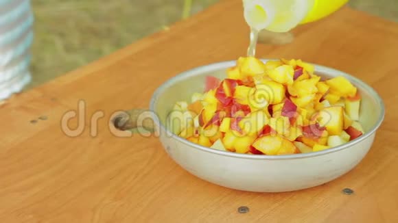 一个年轻的女人把果汁倒进一个盛有水果沙拉的碗里视频的预览图
