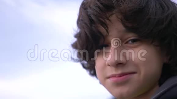 可爱的少年卷发对着蓝天4k慢镜头拍摄视频的预览图