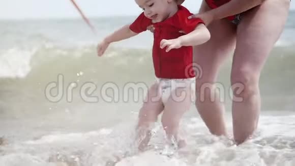 快乐的孩子和奶奶在海边玩耍小男孩开心地笑着笑着在海浪上跳跃视频的预览图