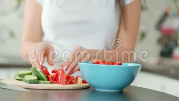 漂亮的年轻女人准备午餐把胡椒放进碗里做沙拉特写视频的预览图