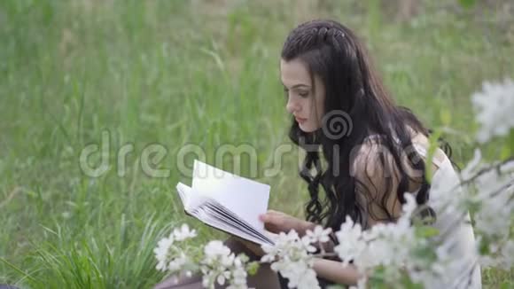 4K年轻女子坐在公园里看书视频的预览图