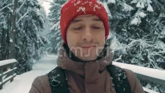 在大雪纷飞的冬季森林道路上徒步旅行的年轻人视频的预览图