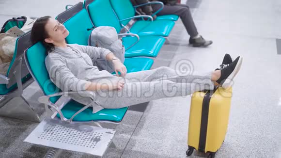 美丽的女人有着深色短发躺在座位上放在行李上视频的预览图