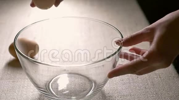 把鸡蛋打碎到玻璃碗里准备烘烤的原料烹饪特写慢动作视频的预览图