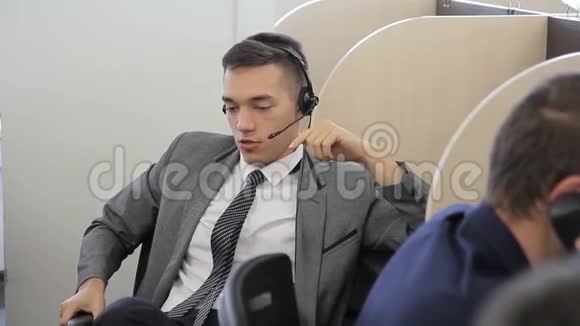 年轻员工正在说话坐在现代办公室时使用耳机视频的预览图