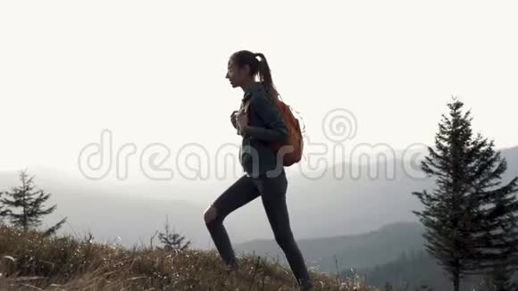 夕阳西下年轻漂亮的女徒步旅行者走在山脊的边缘视频的预览图