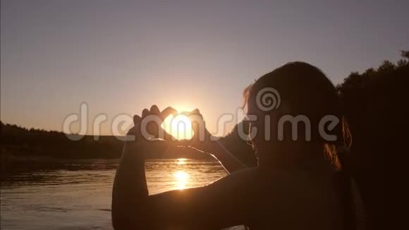 日落时分河边的小女孩双手呈心形视频的预览图
