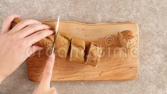 女性的手正在切割木切割板上的黑麦面包视频的预览图