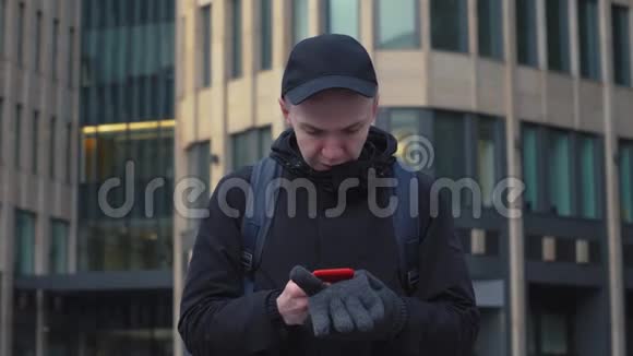 现代城市街头的年轻人在屏幕智能手机上打字视频的预览图