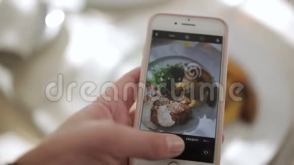 一个男人在一家餐馆里用手机相机为社交网络拍照食物视频的预览图