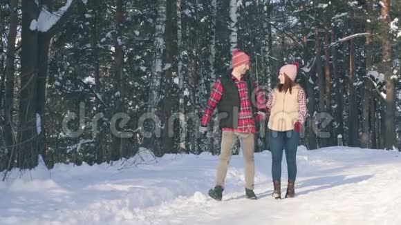 阳光明媚的一天几个穿着冬装的年轻人在雪地森林里漫步公园视频的预览图