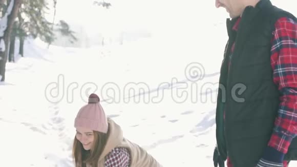 年轻可爱的一对女孩扔雪在冬日的森林里阳光灿烂视频的预览图